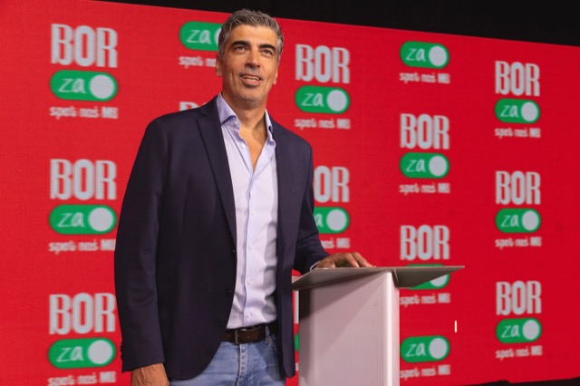 Bor Greiner stoji ob govorniškem pultu pred rdečim ozadjem z znakom BOR za spet naš MB.
